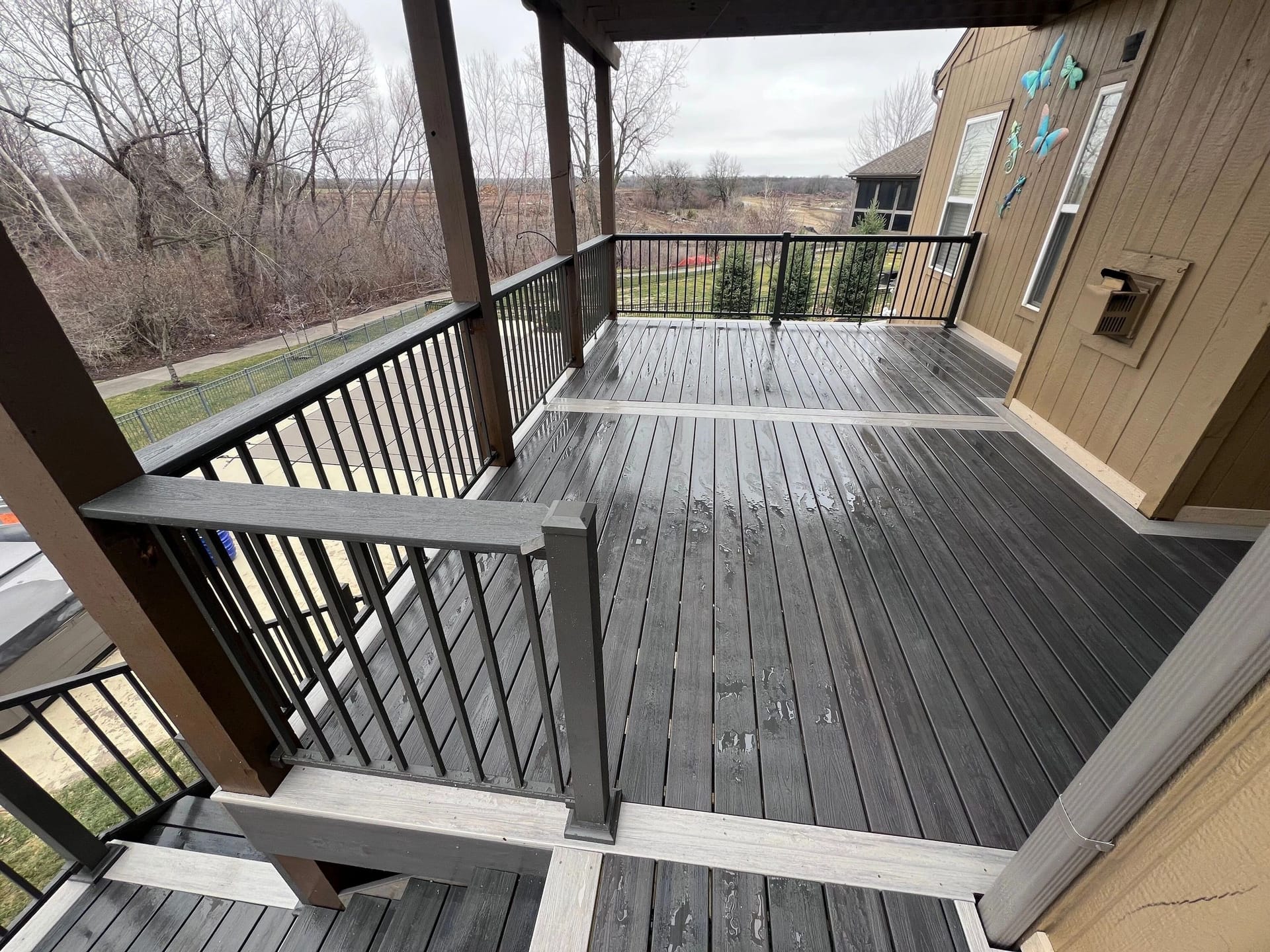 Covered composite deck with gray boards and black railings built by Boyt Home Improvement