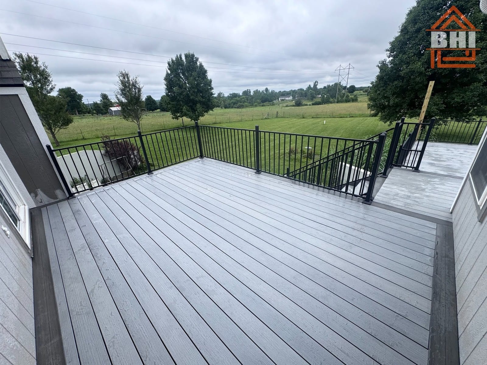 Gray composite deck off the back of a home overlooking a field built by Boyt Home Improvement