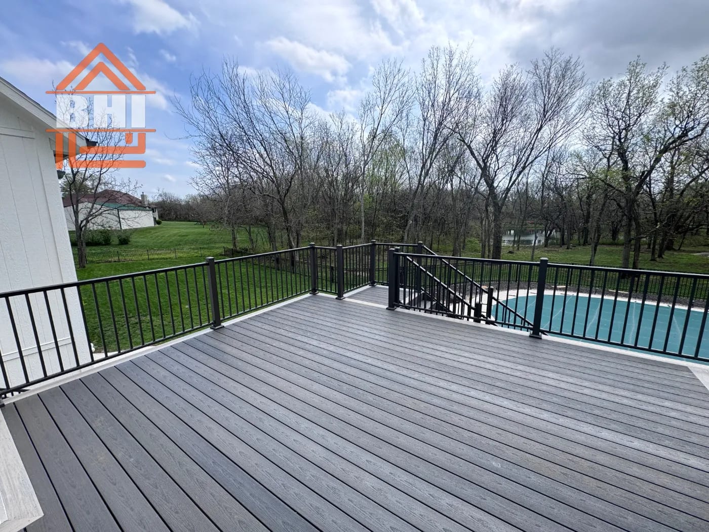 Composite deck with black railing overlooking a backyard pool built by Boyt Home Improvement