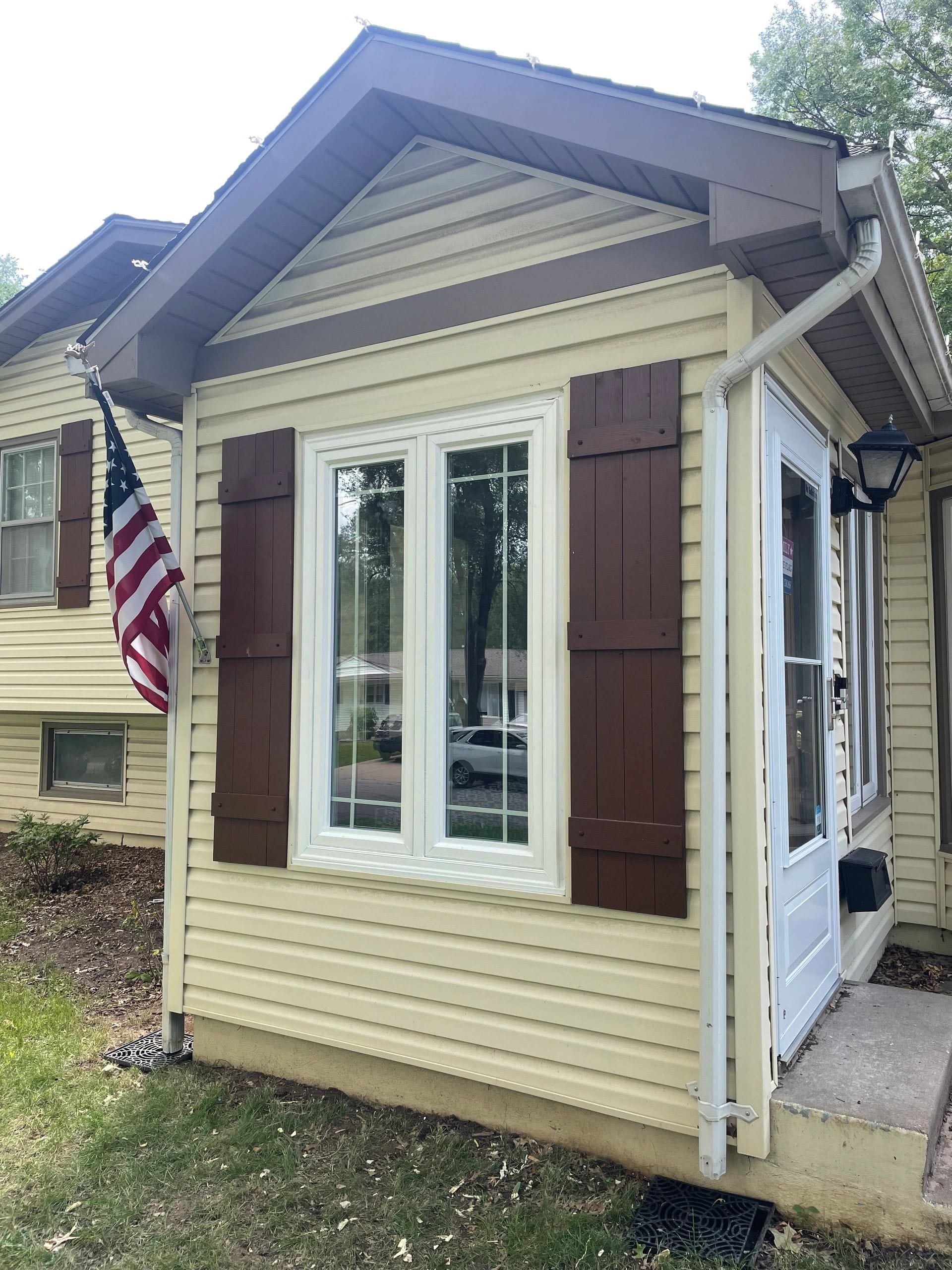 New white-framed windows on a home with brown shutters installed by Boyt Home Improvement